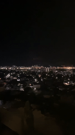 Nighttime aerial view captures illuminated Novorossiysk cityscape and waterfront