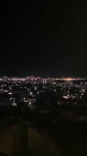 Nighttime aerial view captures illuminated Novorossiysk cityscape and waterfront