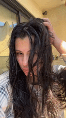 Woman tends hair, takes selfie among plants in Kiryat Bialik
