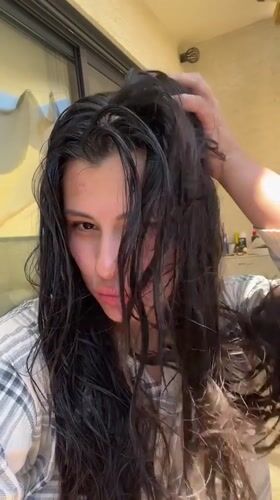 Woman tends hair, takes selfie among plants in Kiryat Bialik