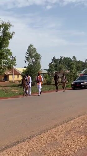 Traditional-dressed group walks roadside in Durimi, Nigeria
