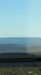 Wind turbines on a Croatian ridgeline, seen from a railing overlook