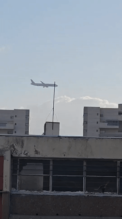 Airplane passes over Holon's skyline on a partly cloudy day