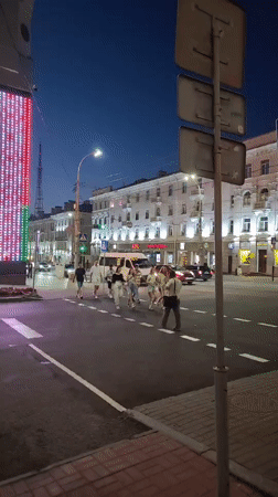 Nighttime street crossing near a lit downtown block in Homyel