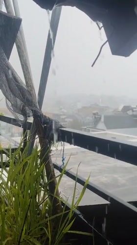 Heavy morning rain obscures Da Lat cityscape from balcony