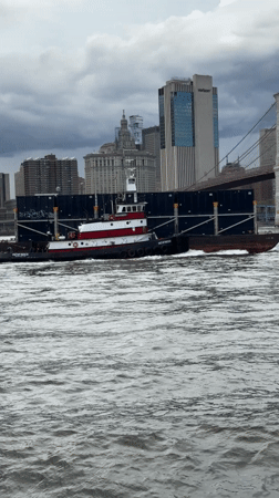 Tugboat and barge navigate New York Harbor Friday evening