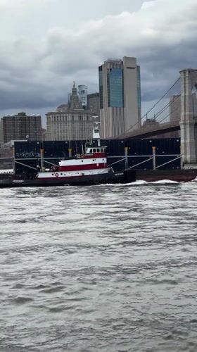 Tugboat and barge navigate New York Harbor Friday evening
