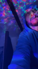 Person in hoodie observed in colorful lit spaces, Bischheim