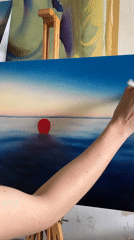 Artist paints seascape with red sun in London