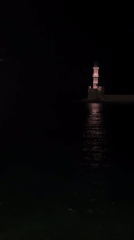 Chania harbor at night — lighthouse, boats, and old town streets