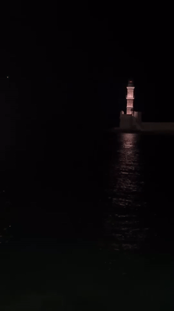 Chania harbor at night — lighthouse, boats, and old town streets