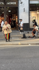 Street musician performs as Ferrari parks on busy London sidewalk