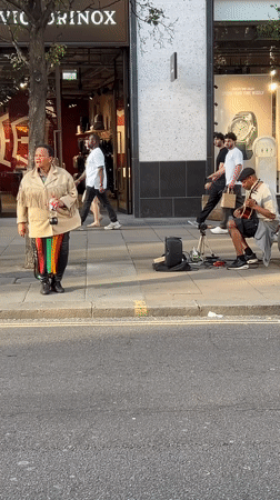 Street musician performs as Ferrari parks on busy London sidewalk