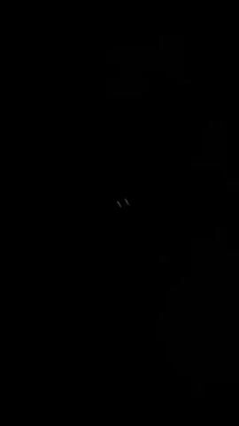The video shows a very dark room, sparsely illuminated with small, dim, irregularly-shaped light sources. These lights include small grids of squares that cycle through different colors like green, purple, and blue. There are also a few small, curved and linear lights in various colors like white, green, and red. The overall environment appears minimal and indistinct due to the limited lighting.