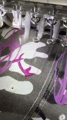 Embroidery machine works purple thread on camouflage fabric
