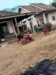 Kids playing and roughhousing in a dry yard in Tanjung Ratu Ilir