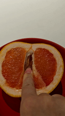 Person touches halved grapefruit in red bowl, Khimki
