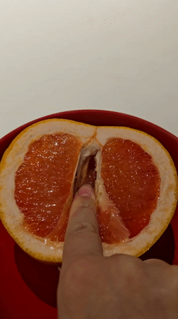 Person touches halved grapefruit in red bowl, Khimki