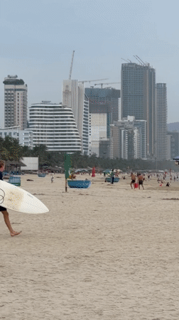 Overcast morning at Đà Nẵng beach, surfers, resorts, and shoreline life