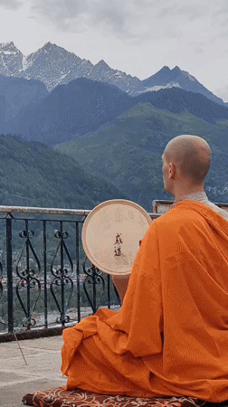 Buddhist monk meditates with drum overlooking Himalayas in Vashisht
