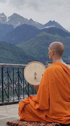 Buddhist monk meditates with drum overlooking Himalayas in Vashisht