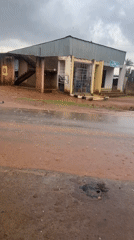 Vehicle navigates flooded red soil road in Nigeria