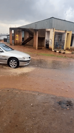 Vehicle navigates flooded red soil road in Nigeria
