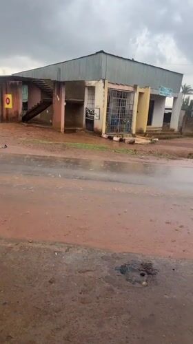 Vehicle navigates flooded red soil road in Nigeria