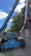 Blue boom lift conducts building work on brick structure