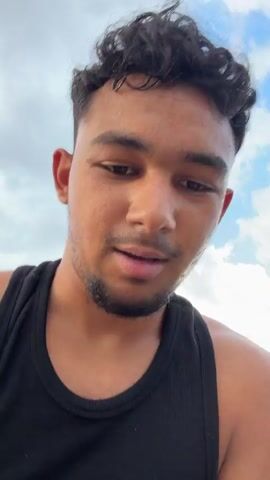 The media file captures a young man in a black tank top standing on a metallic structure, likely a tower or platform, with a breathtaking view of a vast green forest and a distant town under a cloudy sky. The man, with curly dark hair and a light beard, smiles at the camera, displaying a sense of excitement and perhaps a touch of trepidation as he looks down.

The camera pans to reveal the dizzying height from which the footage is being filmed. Below, a dirt road winds through the dense forest, with glimpses of what appear to be small buildings or structures nestled amongst the trees. The metallic structure itself is weathered and shows signs of rust, suggesting it might be an old, abandoned tower.

The scene suggests an adventurous act, possibly exploring or documenting the view from a high vantage point. The time of day appears to be late afternoon or early evening, with soft, diffused light filtering through the clouds. The weather seems mild, with no indication of rain or strong winds. The location, Turiya, Bulgaria, provides a geographical context for the expansive natural landscape. The man's expression conveys a mix of exhilaration and awe, as he embraces the thrill of being so high up and surrounded by nature's beauty.