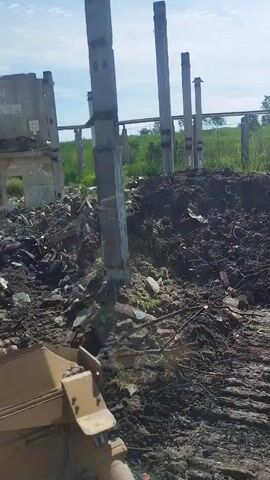 The video shows a construction site, possibly a demolition or renovation project. There are concrete pillars standing in a line, with some unfinished building structures visible in the background. The ground is covered in dirt, debris, and rubble, suggesting recent activity. The lighting indicates it is daytime, with a clear sky. There are no people visible in the footage.
