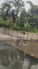 Boy walks bicycle through shallow water in Saweuk, Indonesia