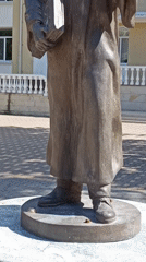 Bronze statue, a pet food billboard, and roses in bloom