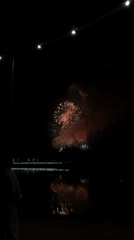 Fireworks display lights up Krasnoyarsk waterfront near illuminated bridge