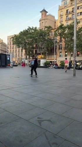 Skateboarders practice tricks in Barcelona plaza evening session