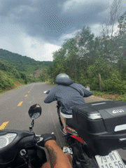 Motorcyclists travel rural road under dramatic skies in Vietnam