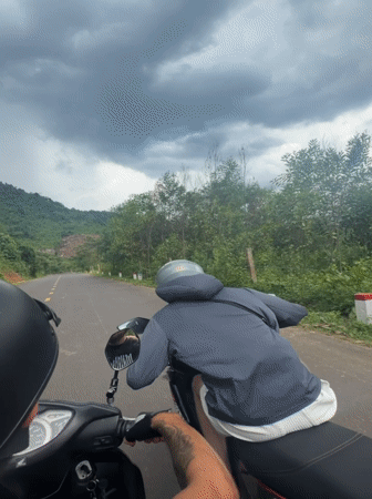 Motorcyclists travel rural road under dramatic skies in Vietnam
