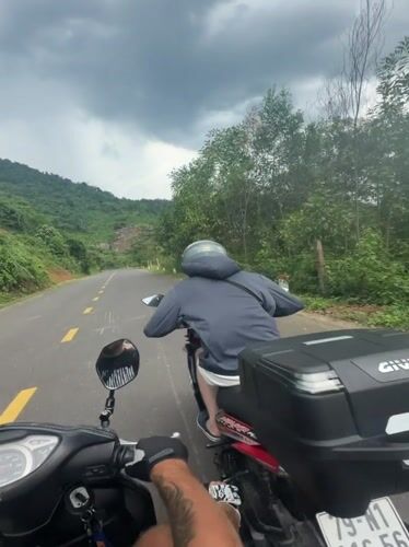 Motorcyclists travel rural road under dramatic skies in Vietnam