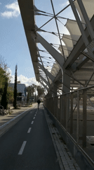 Pedestrian walks under modern canopy structure in Tel Aviv