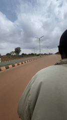 Motorcyclist in green jacket travels paved road in Nigeria