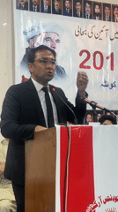 Large indoor gathering in Quetta hall with podium speakers and banners
