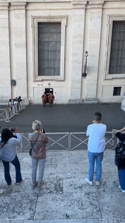 Tourists photograph Swiss Guards in Vatican City courtyard