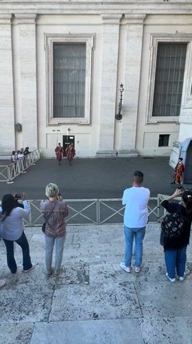 Tourists photograph Swiss Guards in Vatican City courtyard