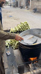 Street vendor roasts corn using hot sand method in Multan