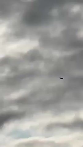 Certainly! Here's a description of the video:

The video shows a distant silhouette of a jet aircraft against a backdrop of heavy, gray, cloudy sky. The plane appears to be flying straight and level. There's no visual indication of the plane's make or model due to the distance and poor lighting. The sky is completely overcast, creating a dark and potentially ominous atmosphere.