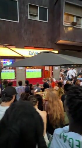 Milan crowd gathers at outdoor bar to watch big screens