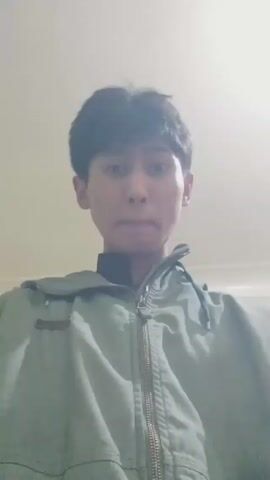 A young man with dark hair stands in a room. He is wearing a green jacket. The room has light green walls and a white ceiling. The camera moves around slightly as the man looks at the camera.