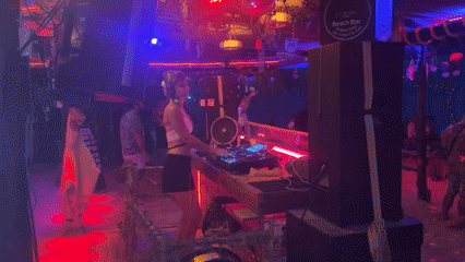 DJ performs at illuminated beach bar in Thailand