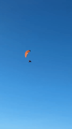 Two orange and black paragliders soar over Petten skies