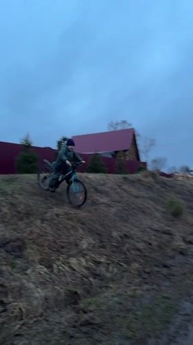 Boy rides mountain bike through muddy terrain in rural Russia